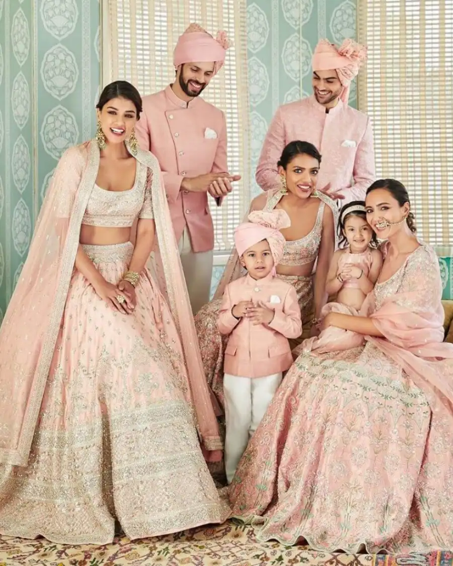 Family in matching pink traditional outfits, posing together.