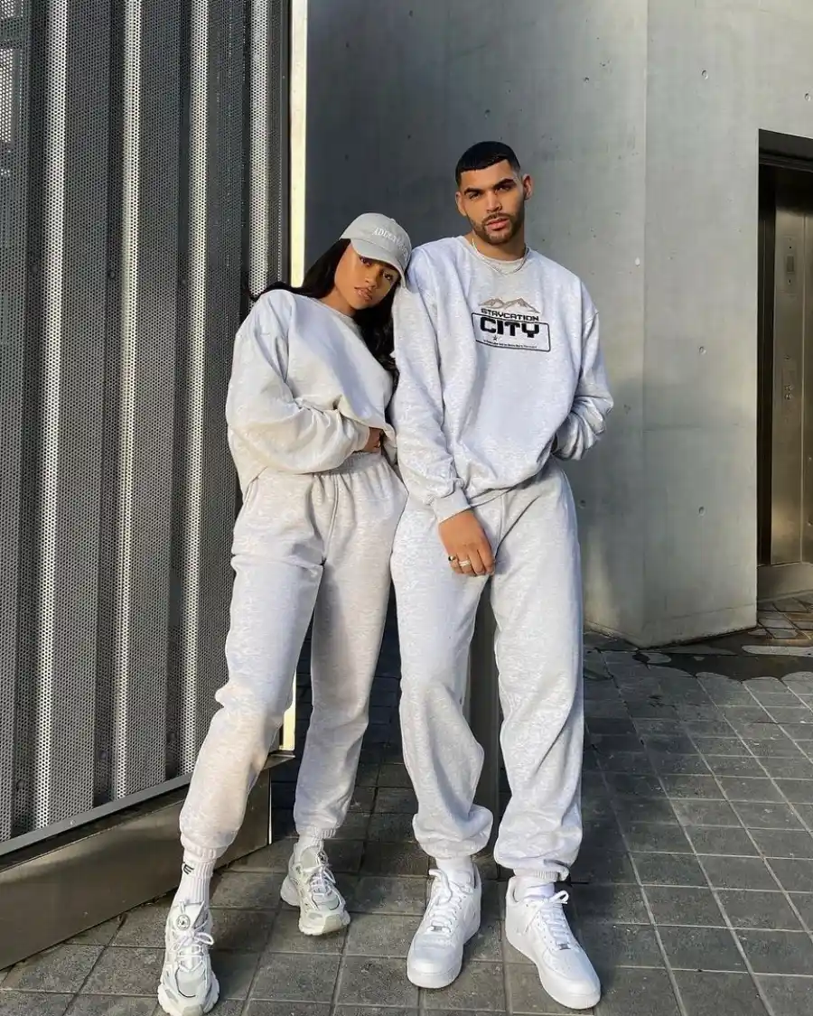 Couple wearing matching sweatshirts and sneakers outdoors.